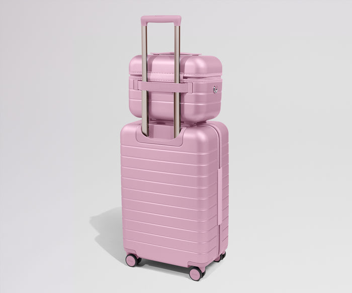 Pink suitcase with a smaller pink suitcase on top against a light gray background