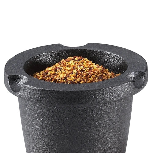 Black cast iron spice grater container with ground spices on a white background.