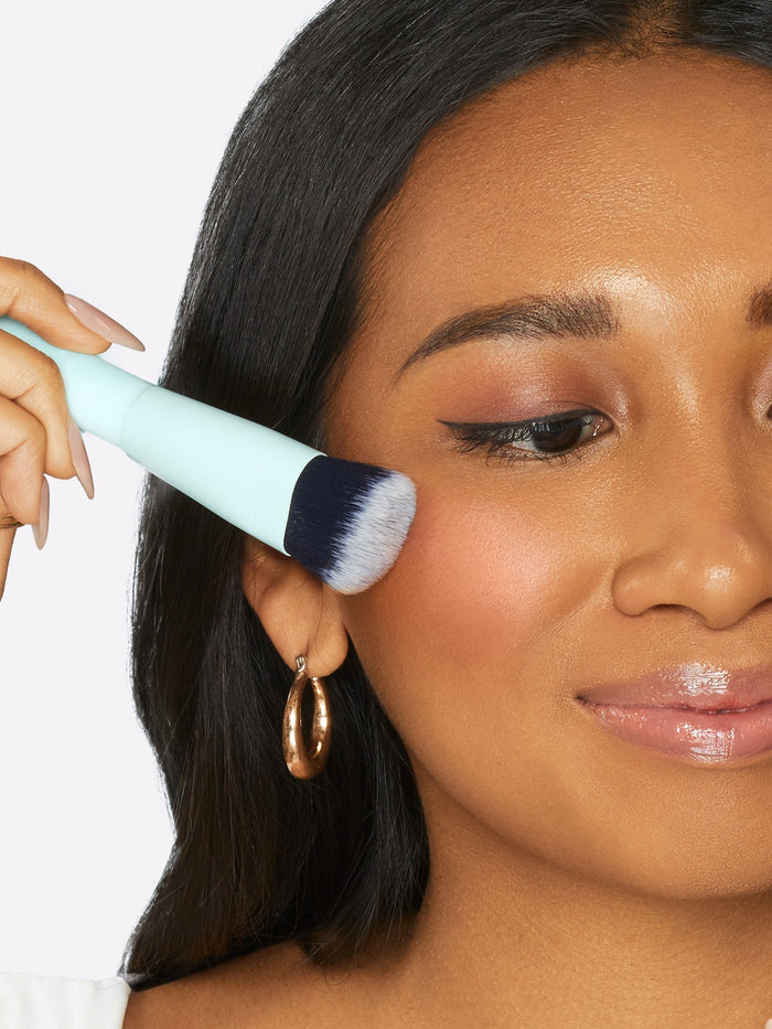 Woman applying makeup with a brush on a white background