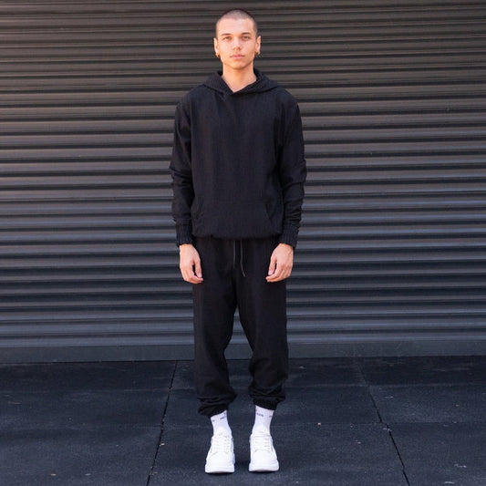 Martin Valen men's oversized black corduroy tracksuit set, front view with hoodie and joggers, white sneakers visible