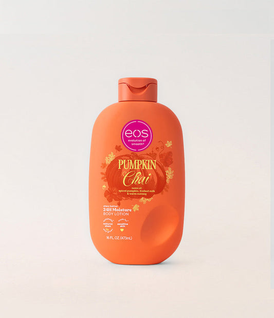 A bottle of EOS Pumpkin Chai body lotion on a light gray background. The bottle is bright orange with a matching flip-top cap, featuring a label with a pink EOS logo and autumn-themed graphics.