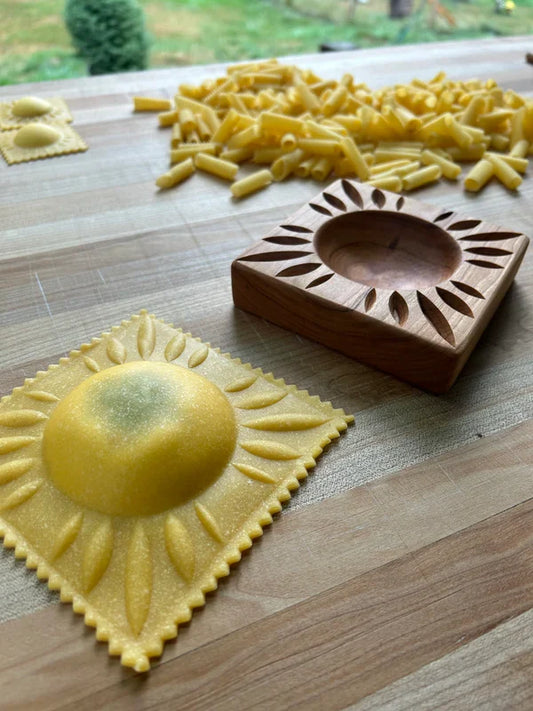 Wooden pasta mold with sunflower design on a wooden surface